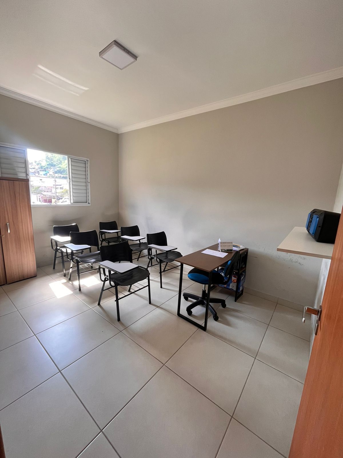 Sala de cursos do Shooting Club com carteiras e mesa do instrutor